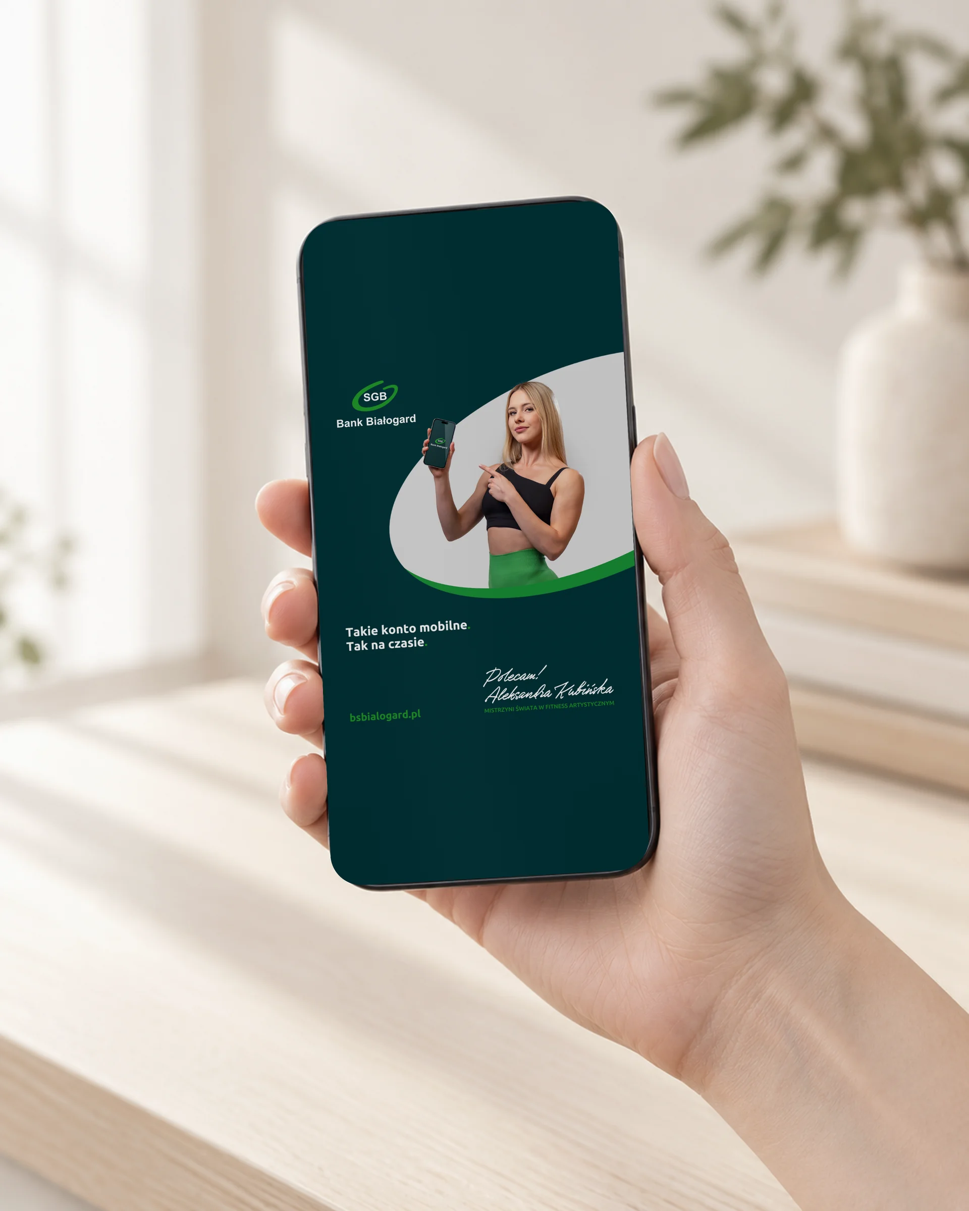 Smartfon w dłoni z pionową reklamą Takie Konto Mobilne