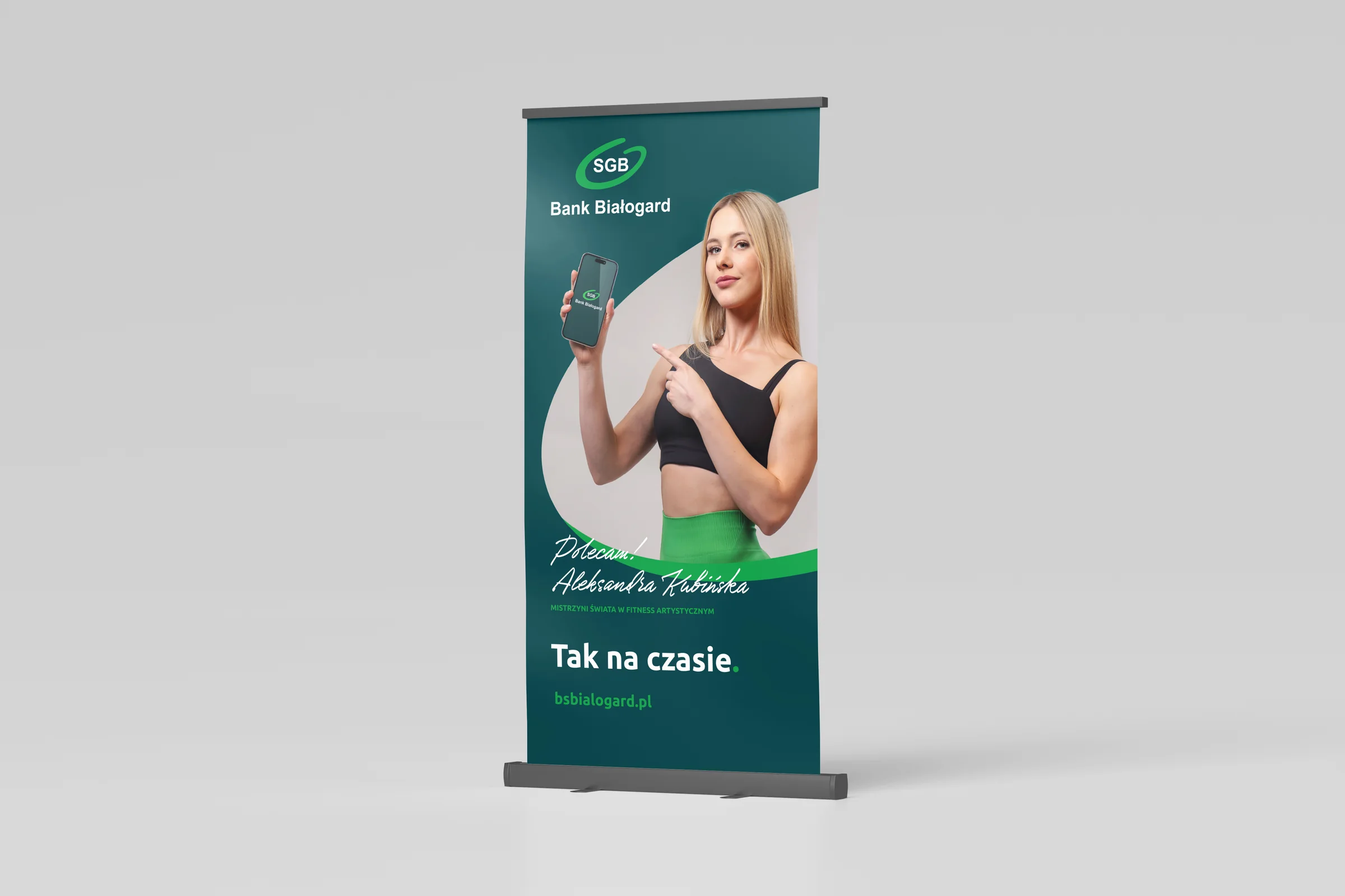 Roll-up kampanii Tak na czasie z Aleksandrą Kubińską trzymającą telefon